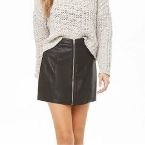 A faux leather mini skirt featuring a zippered front and an A-line silhouette.